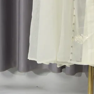 Detalle del vestido largo bordado crema con botones decorativos y motivo de hojas