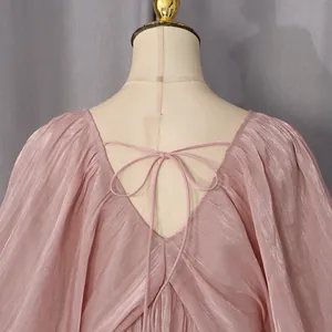 Gros plan du dos d'une robe rose scintillante avec col en V et détail de nœud.