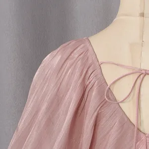 Gros plan sur une robe rose plissée scintillante avec col en V et nœud à l'arrière