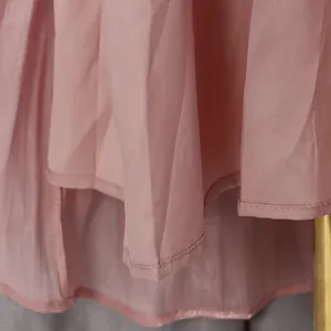 Gros plan montrant les coutures fines et le tissu en mousseline rose du robe longue