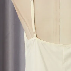 Detalle en primer plano de la fina tira ajustable en un vestido de color crema.