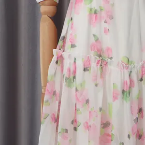 Macro view showing the delicate pink rose floral print and ruffled layers of the chiffon dress