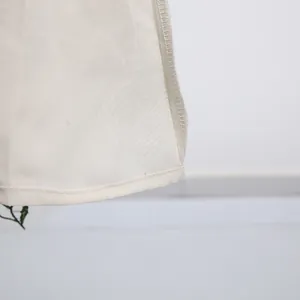 Detailopname van de zoom en het fijne stiksel van een witte geborduurde Franse jurk.