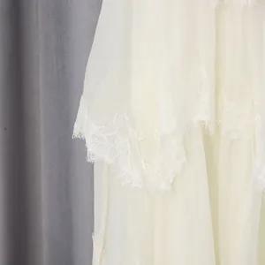 Close-up detail showing the intricate lace trim and layered fabric of the cream dress.