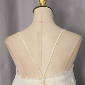 Elegant close-up showing the delicate lace-trimmed back and thin straps of a white camisole dress.