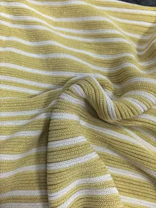 Close-up of yellow and white striped knitted fabric with subtle golden lurex sparkle.