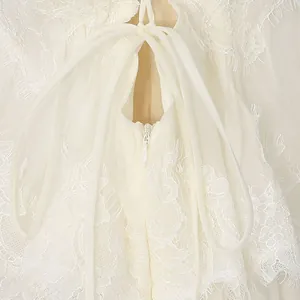 Detailed macro view of white floral lace embroidery and back zipper on a tiered long dress