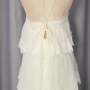 Detailed back view of white lace tiered camisole dress with delicate ruffle edges