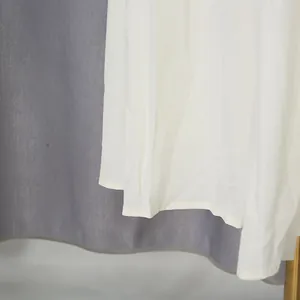 Detail of white tiered long dress hemline showing clean stitching and fabric texture.