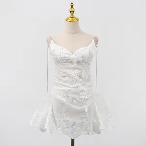 Détail d'une élégante robe courte en dentelle blanche avec broderie papillon et bretelles chaîne