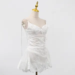Détail de la broderie de dentelle blanche complexe sur une élégante robe courte à bretelles