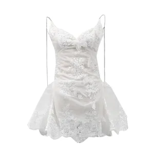 Détails de la robe courte en dentelle blanche avec broderie papillon et bretelles.