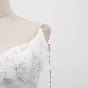 Détail montrant la broderie papillon en dentelle blanche et la bretelle chaîne argentée