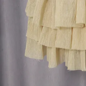 Close-up of layered cream ruffled fabric with elegant crinkled plissé texture details.