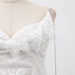 Gros plan détaillé d'une robe en dentelle blanche avec broderie papillon raffinée.