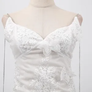 Gros plan détaillé d'une robe en dentelle blanche avec broderie papillon et fines chaînettes