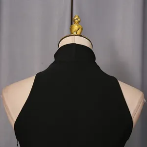 Macro view of the high neck collar and sleeveless tailoring on a minimalist black dress