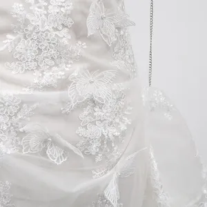 Détail d'une élégante robe en dentelle blanche avec broderies papillons 3D