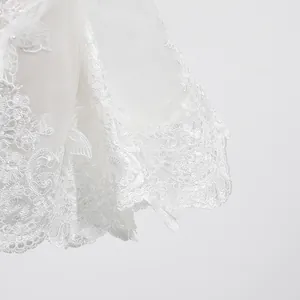 Détail de la broderie en dentelle florale blanche et de l'ourlet festonné sur la robe