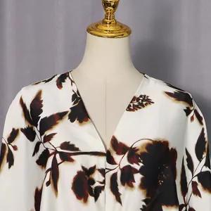 Detail view showing the deep V-neckline and dark floral print on a white loose-fit summer dress