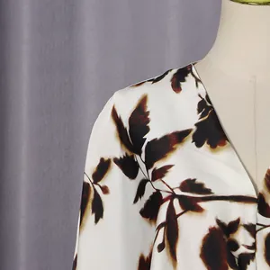 Close-up detail of the elegant leaf pattern fabric on a stylish white V-neck casual dress