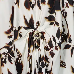 Macro view of an ornate decorative metal buckle on a floral printed satin dress