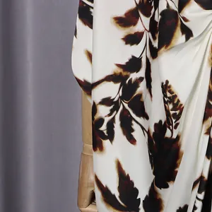 Detailed view of the artistic leaf pattern on the soft white fabric of this dress