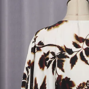 Close-up detail of dark botanical leaf print on a white relaxed fit casual dress fabric