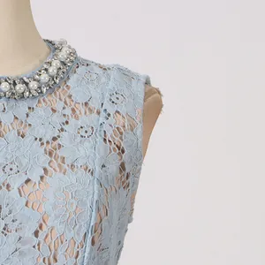 Detailopname van lichtblauwe kanten jurk met elegante halslijn met parels en kristallen kralen