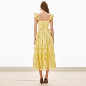 Vista posteriore di un completo giallo due pezzi con crop top e gonna midi ricamata