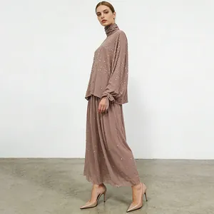 Elegant side view of a women's rhinestone turtleneck top and long A-line skirt two-piece set