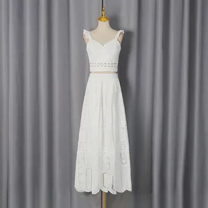 Elegante set da spiaggia bianco due pezzi con crop top a volant e gonna in pizzo traforato.
