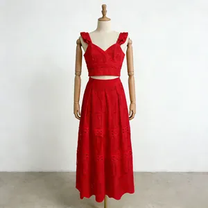 Completo rosso con top a volant e gonna ricamata esposto su un manichino in legno in studio
