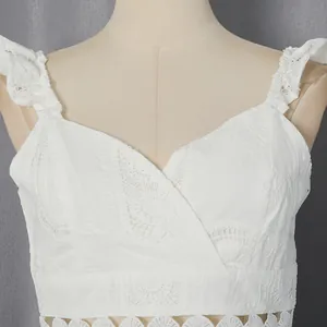 Dettaglio del ricamo in pizzo bianco su un crop top con scollo a V e volant per vacanze.