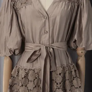 Close-up of French style V-neck dress with puff sleeves and floral lace hem detail.