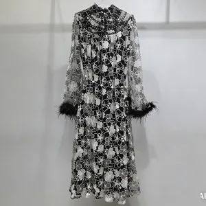Close-up of elegant black lace dress featuring white floral embroidery and feather cuffs
