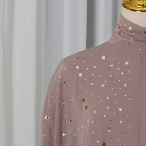 Close-up detail of mauve high-neck top featuring elegant rhinestone embellishments.