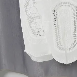 Dettaglio ravvicinato della complessa ricamo in pizzo bianco sul set moda vacanza