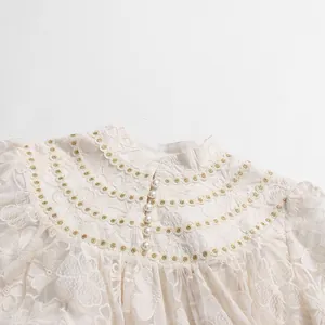 Detail of elegant white lace holiday dress with pearl buttons and gold embroidery trim