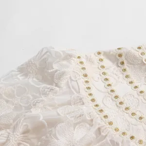 Close-up of intricate floral lace embroidery and delicate gold trim on elegant white dress