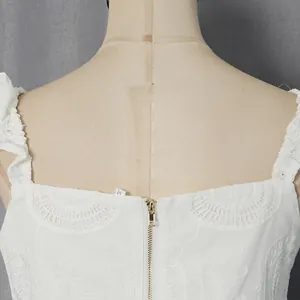Primo piano di alta qualità del retro di un top in pizzo bianco con una zip dorata