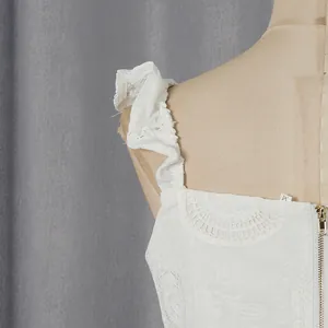 Vista dettagliata di un crop top bianco con spalline a volant e ricami floreali