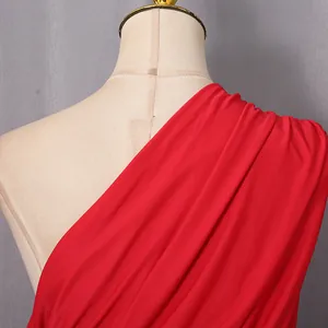 Primo piano di un elegante abito rosso monospalla con dettagli plissettati su manichino.