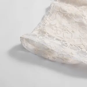 Detailed macro view of white floral lace embroidery on an elegant dress sleeve cuff