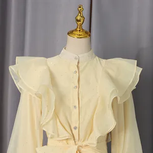 Close-up of ruffled high collar and shoulder details on a cream-colored vintage style dress.