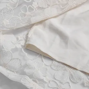 Detailed view of delicate floral lace embroidery and smooth lining on a white vacation dress