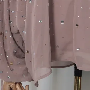 Close-up of dusty rose chiffon fabric with sparkling rhinestone and crystal embellishments