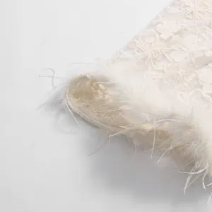 Close-up of elegant floral lace embroidery and soft feather trim on a dress sleeve