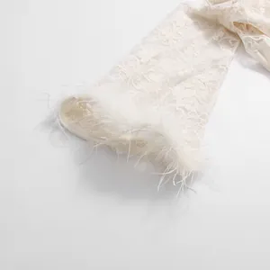 Close-up of white lace dress sleeve featuring elegant floral embroidery and feathered cuffs