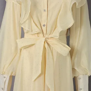 Detail of romantic vintage dress featuring ruffles, a waist tie, and sparkling rhinestones